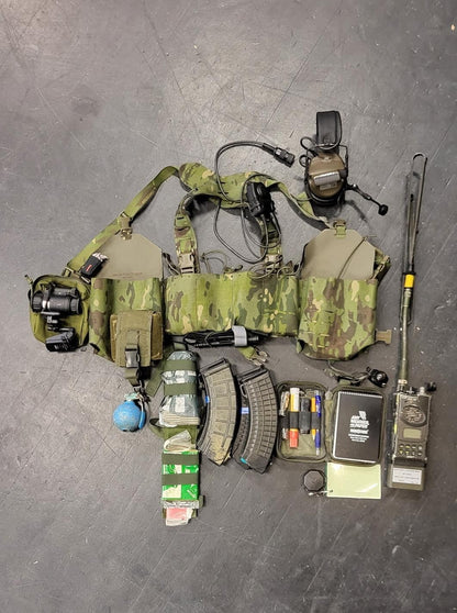 Adversary Force L4 WCSIG Chest Rig in Multicam mit Magazintaschen, Funkgerät und Ausrüstung auf dunklem Untergrund.